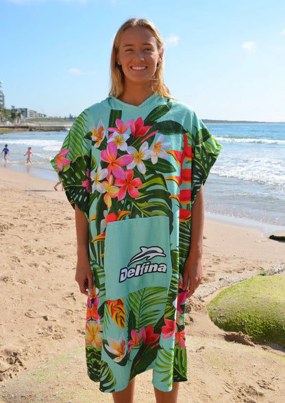 Person wearing a colorful tropical patterned poncho on a beach with ocean and sky in the background